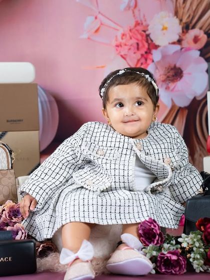 A sweet smile from our stylish queen. The soft pink background and floral accents add a touch of elegance to this high-fashion shoot.