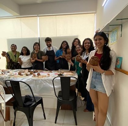 A group of participants from a pottery workshop, all holding their unique creations. The sense of community is a big part of the Art Beat experience.