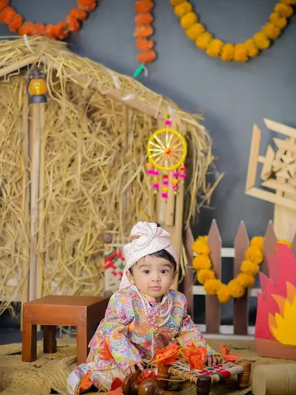 A full view of the Lohri setup, showing the baby sitting near the bonfire and charpai, surrounded by colorful props that celebrate Punjabi culture.