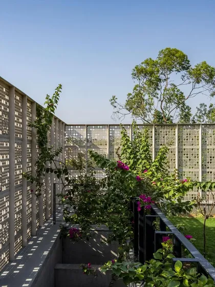 Perforated concrete screens enclose a garden space, creating a private outdoor room that is both shaded and airy. The play of light through the screens animates the surfaces.