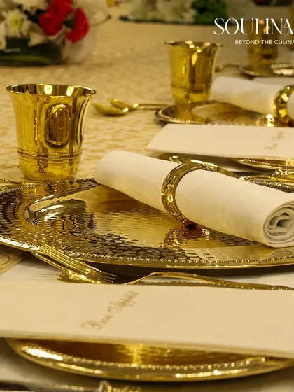 The epitome of traditional luxury, this close-up shows a meticulously arranged place setting with hammered gold plates and goblets. We honour heritage by blending it with our impeccable service for a truly royal dining experience.