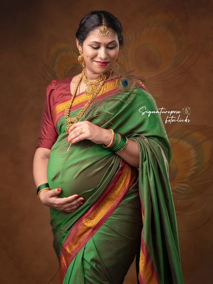The rich green of the silk saree and the traditional jewelry are the focus of this elegant close-up.