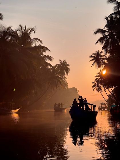 A silhouette of a boat and its passengers against the setting sun in Honnavar, a perfect travel photograph.