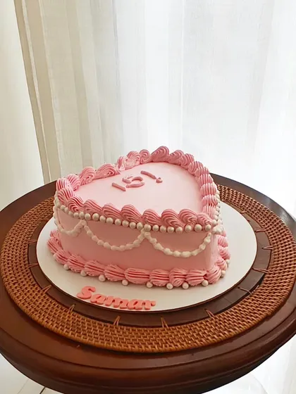 A sweet, pink heart-shaped vintage cake for a 15th birthday. The delicate pearl-like piping gives it a classic, elegant feel.