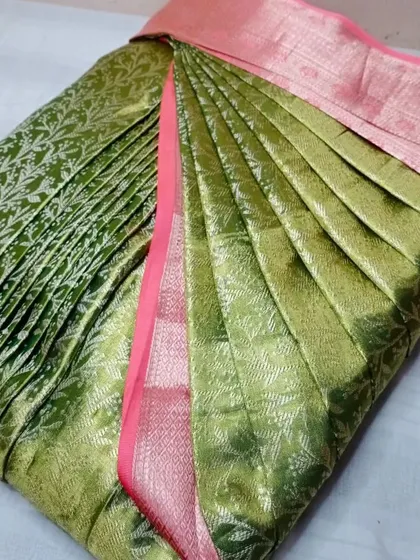 A light green brocade saree with a pink border.