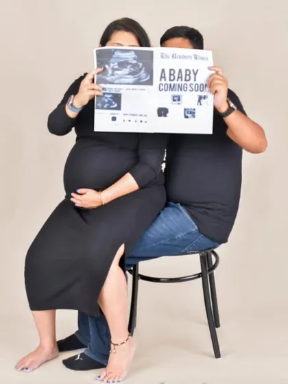 I love incorporating fun and personal ideas into a shoot. Here, the couple uses a custom newspaper prop to announce their "coming soon" arrival, making for a playful and memorable portrait.