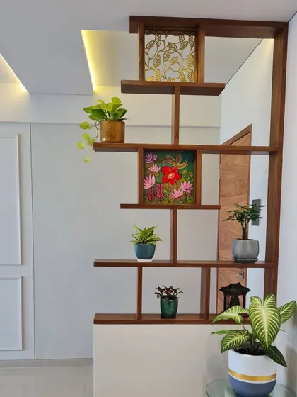 This wooden shelving unit acts as a beautiful and practical room divider. We helped the client select a variety of indoor plants with different shapes and sizes to style the shelves, adding life and color while still allowing natural light to filter through the space.