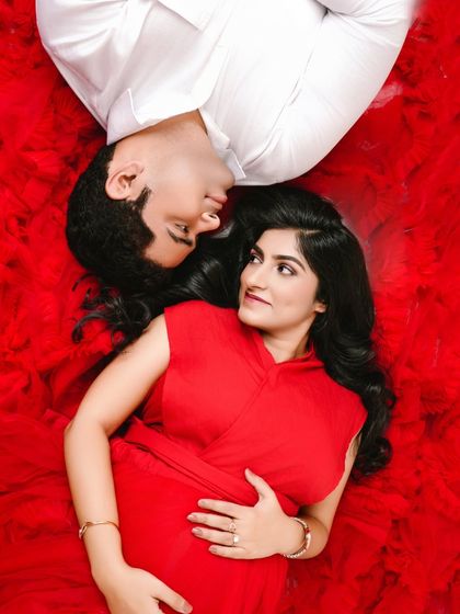 A creative overhead shot capturing the couple surrounded by a sea of red. This artistic portrait symbolizes the all-encompassing love that is about to welcome a new life.