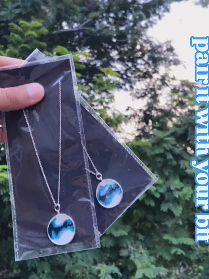 A pair of matching 'wave' necklaces, perfect for you and your best friend. The design mimics ocean waves in shades of blue and white.
