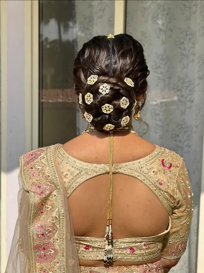 For this bride's wedding day, I created this intricate and elegant bun. The hair is woven beautifully and adorned with traditional gold accessories for a regal finish.