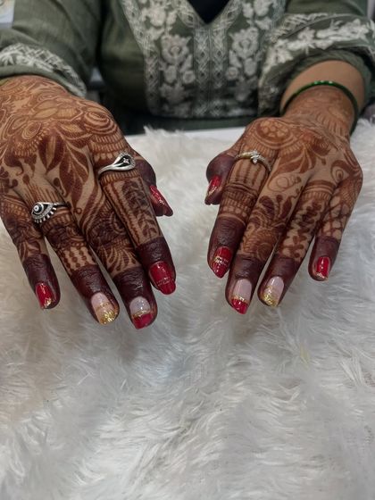 Gel polish on natural nails can be perfect for bridal events too. Here, I combined a classic red with a subtle gold glitter ombré and delicate line work to match her festive attire and mehndi.