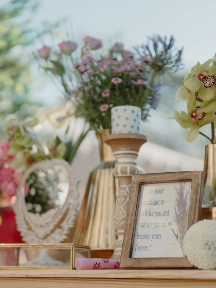 A curated shelf of props, including a vintage mirror, a framed quote, and small floral arrangements.