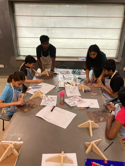 An instructor guides a group of students as they work on their woodcut designs, ensuring they learn the carving techniques safely.