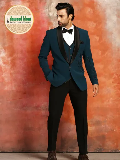 This is a modern take on the classic tuxedo, tailored in a striking teal fabric. The design features a contrasting black shawl lapel, a single-button closure, and a slim fit, offering a sharp and contemporary option for formal events.