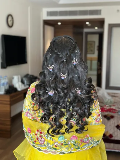A Haldi hairstyle with curls, twists, and colorful butterfly accessories.