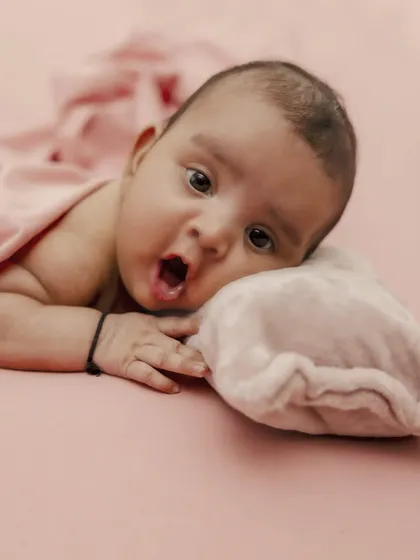 A moment of surprise and wonder from this little one. This simple portrait on a soft pink background captures a fleeting expression, showing that even the quiet moments are full of personality.