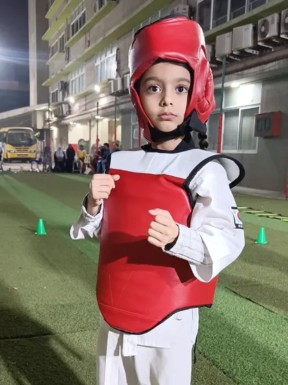A young student stands ready in his protective gear. Sparring teaches invaluable lessons in distance, timing, and strategy, all within a safe and controlled environment.