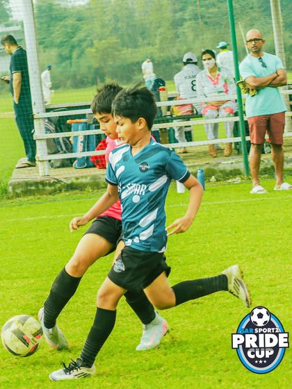 Intense one-on-one action as a player in a blue jersey tries to dribble past a determined defender during a crucial Pride Cup game.