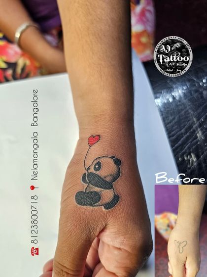 A small butterfly tattoo on the hand was covered with this cute panda holding a heart balloon.