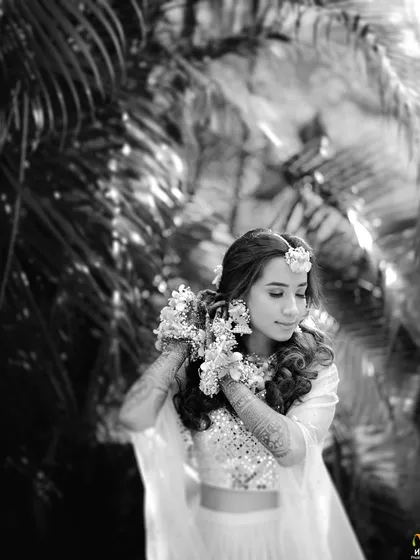 A beautiful black-and-white portrait of a Haldi bride, highlighting the texture and shape of her floral jewellery.