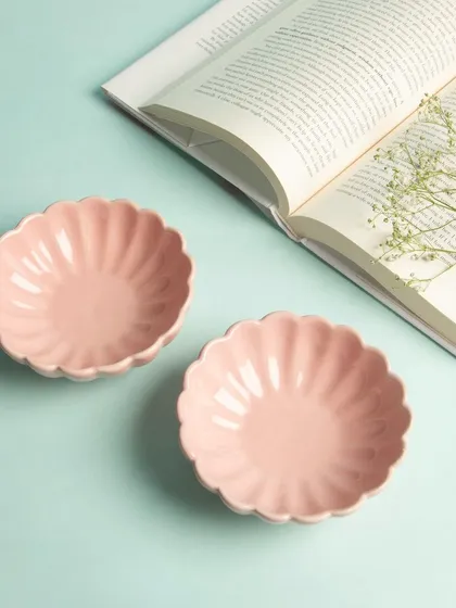 Two pink, flower-shaped ceramic bowls styled with an open book, creating a peaceful and charming lifestyle scene.