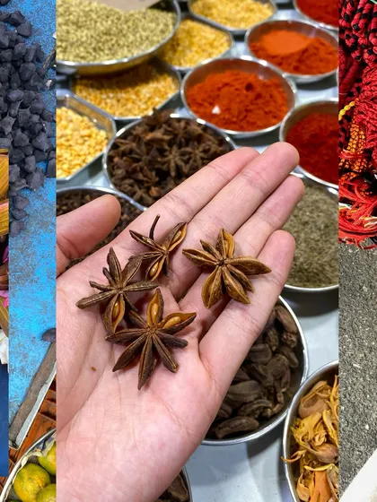 A hand holding star anise over a spread of spices, a sensory snapshot from the market.