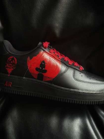 A custom black Nike Air Force 1 featuring Itachi Uchiha from Naruto sitting under a blood-red moon.