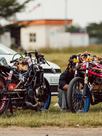 Two custom-built drag bikes, stripped down to their bare essentials, being prepped by their builders. This is where passion and engineering meet.