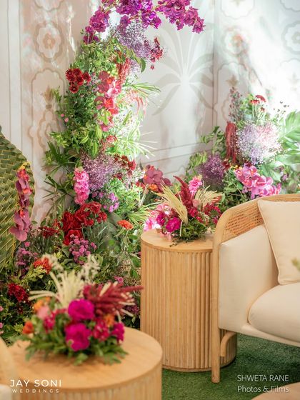 A beautiful composition of seating and florals at the entrance, where the textures of the cane-back chair and the lushness of the flower arrangements create a rich visual experience.