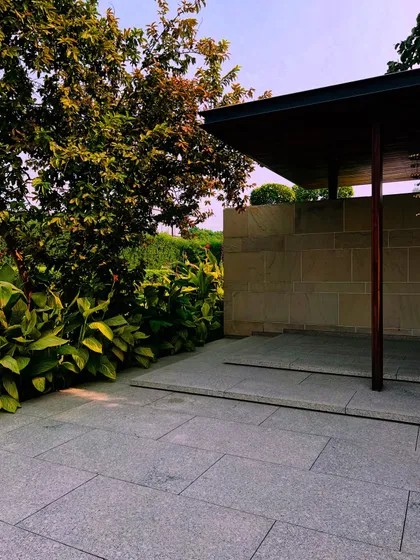A covered patio area with stone flooring and walls, surrounded by lush plants, providing a seamless transition between the indoors and the garden.