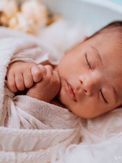 A detailed shot of a newborn's face and clasped hands. This angle captures the peacefulness of a sleeping baby and the tiny, perfect details you'll want to remember forever.