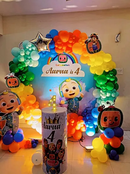 A bright and cheerful Cocomelon theme for a 4th birthday. This decoration features a rainbow balloon arch and multiple character cutouts around a personalized backdrop.