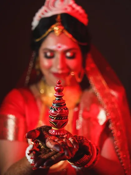 The beauty of tradition is in the details. This portrait of a beautiful Bengali bride focuses on the 'sindoor daan' ritual, using rich red lighting to highlight the significance and emotion of the moment.