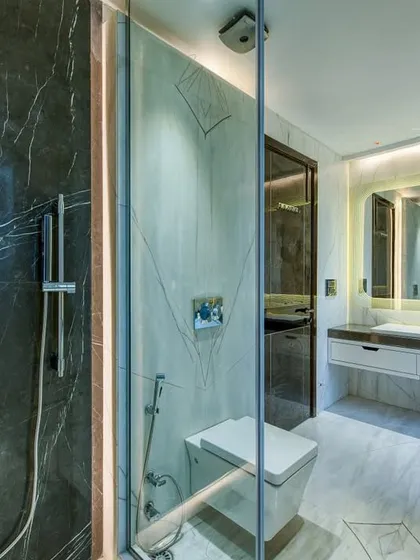 A master bathroom concept featuring a mix of dark and light marble. The glass-enclosed shower with a modern digital control panel adds a high-tech touch.