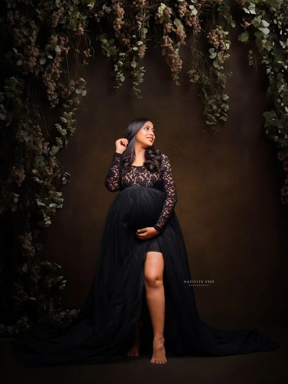 A beautiful portrait in a black lace gown, set against a lush, dark floral backdrop. This creates a romantic and slightly mysterious atmosphere.