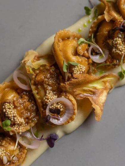 Here, handmade corn and ricotta tortellini are the star. They are served on a bed of parsnip puree and finished with burnt scallion, a hint of chili butter, and pickled mustard for a beautiful interplay of sweet and smoky flavors.