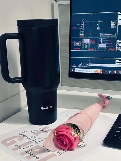 A small token of appreciation for the women on our team. A single rose and a personalized tumbler on a desk, with architectural drawings in the background, symbolizing the blend of creativity and precision they bring to our work.