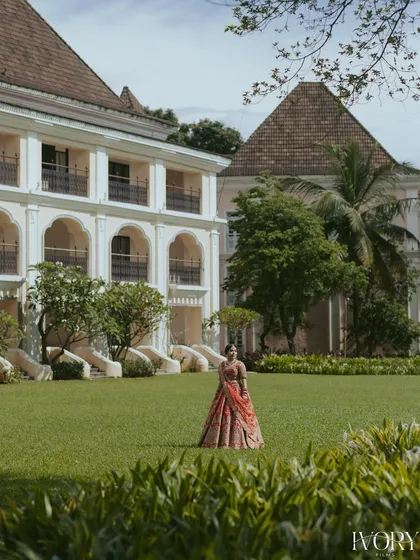 A beautiful portrait of the bride in the lush green lawns of her Goa wedding venue. The grand architecture in the background adds to the sense of a destination fairytale.
