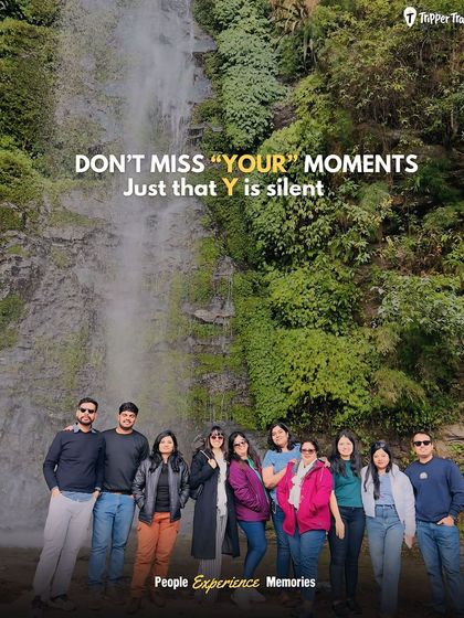 Don't miss your moments, just that the 'y' is silent. A fun group picture in front of a waterfall in Bhutan, reminding us to live fully and cherish every experience.