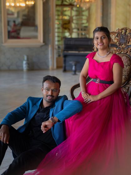 A stylish and modern pre-wedding portrait. The vibrant pink gown and the partner's blue blazer create a bold and fashionable color combination.