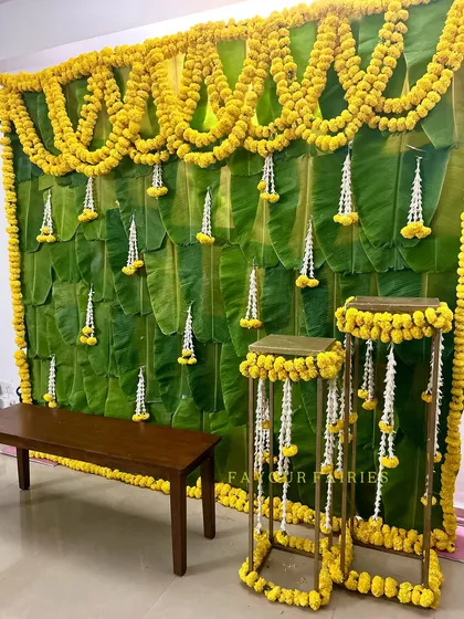A traditional South Indian decor backdrop created with fresh banana leaves, marigold garlands, and hanging jasmine flowers. This is perfect for housewarming or pooja ceremonies.