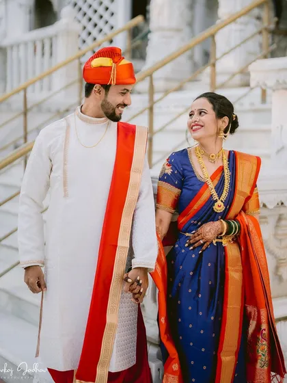 Walking hand-in-hand, Sayali and Gaurav share a look of love. The groom's vibrant red and yellow turban adds a pop of color to this classic Maharashtrian wedding portrait.