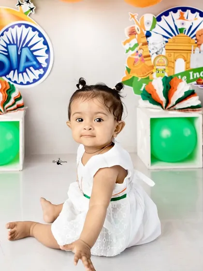 A simple and beautiful portrait of a baby girl in a white dress with a tricolor belt, celebrating the spirit of India.