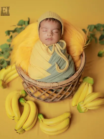 A closer view of the banana-themed shoot, showing the baby swaddled in coordinating yellow and grey wraps. The vibrant colors make these photos pop.