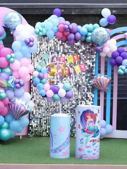 The main photo backdrop for the Mermaid theme. A sparkling sequin wall, character cutouts, and themed props like shells and "BABY" blocks make it a stunning centerpiece.