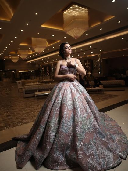 A client posing in a grand ballroom wearing a metallic-sheen ball gown. The unique fabric and full skirt make this a standout piece for any formal event.