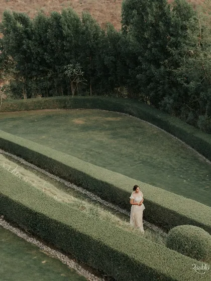 A bride lost in a garden maze. This high-angle shot creates a sense of solitude and romance, like a scene from a classic film.