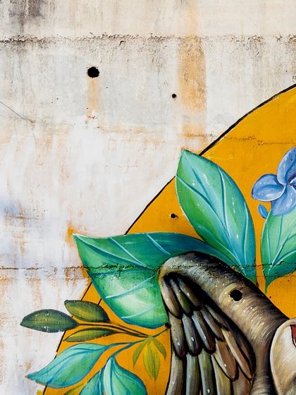Detail of the Sarus crane from the Coorg mural, set against the raw texture of the concrete wall.