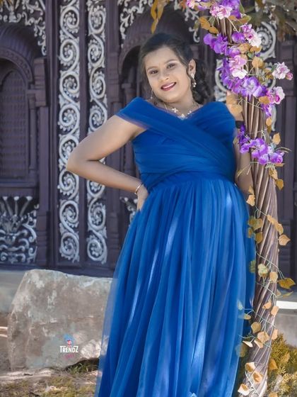 A graceful solo portrait in a royal blue gown. The pose is elegant and confident, set against an ornate backdrop that adds a touch of sophistication.