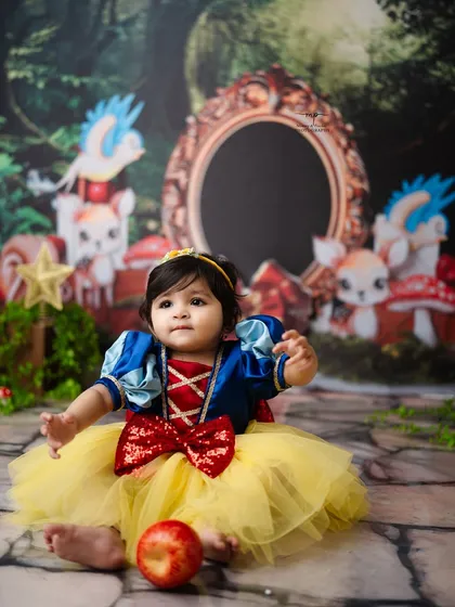 A perfect portrait of a sitting Snow White, holding a bright red apple. The details in her costume and the magical forest backdrop make this photo truly special.